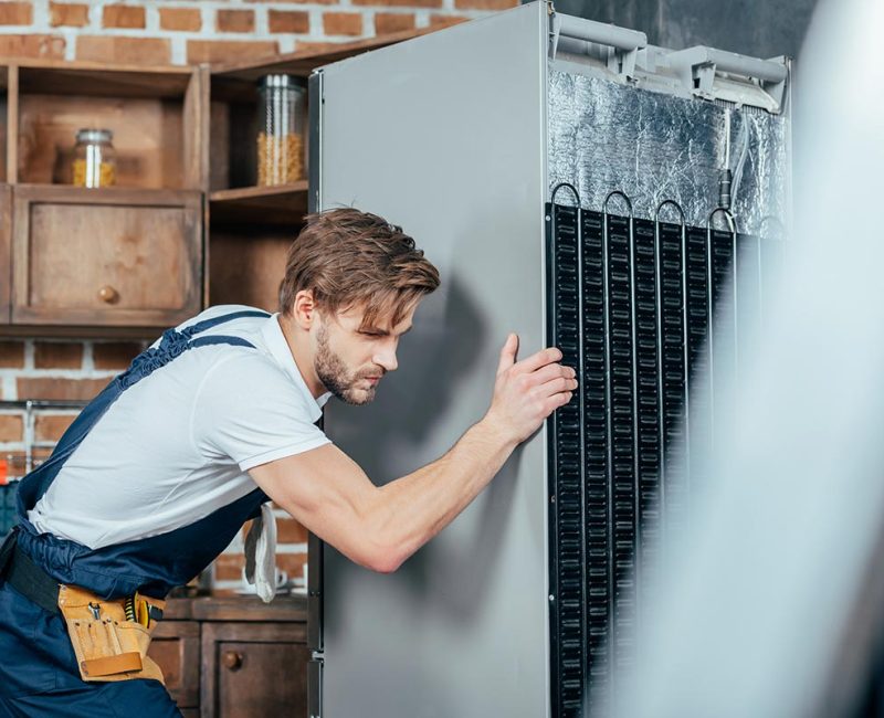 young-repairman-in-protective-workwear-moving-refr-resize.jpg